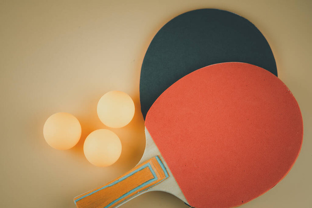 オレンジ色の背景に卓球やピンポンのラケットとボール2つ - 写真・画像