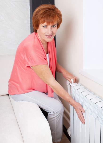 Woman controls the temperature of the radiator - Fotó, kép
