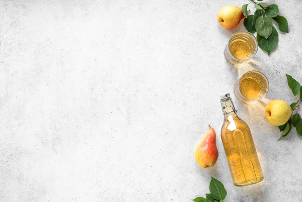 Pear cider drink or fermented fruit drink  in glasses and bottle and organic pears on white, top view, copy space. Healthy homemade hard pear cider recipe. - Фото, зображення