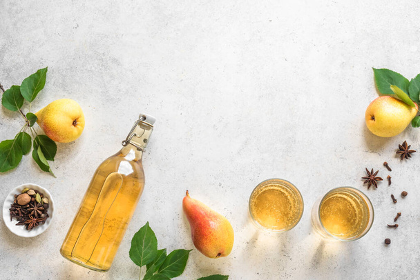 Pear cider drink or fermented fruit drink  in glasses and bottle and organic pears on white, top view, copy space. Healthy homemade hard pear cider with spices. - Φωτογραφία, εικόνα