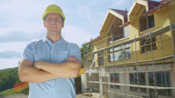 PORTRAIT: Ο ανάδοχος χαμογελά μπροστά σε ένα σύγχρονο υπό κατασκευή σπίτι. - Πλάνα, βίντεο
