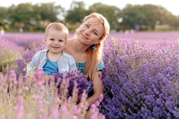 Feliz joven madre y su pequeño hijo posando en el campo púrpura de flores de lavanda
 - Foto, imagen