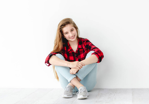 Smiling teenage girl sitting on floor - Foto, Imagen
