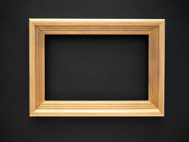 Gold colored wooden frame isolated on a black background. for photos, text, images or paintings - Φωτογραφία, εικόνα