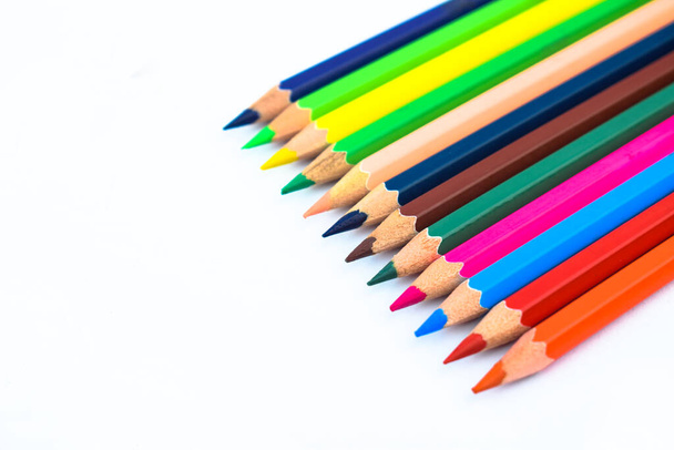 Crayon en bois de différentes couleurs placé sur un fond de papier blanc - Photo, image