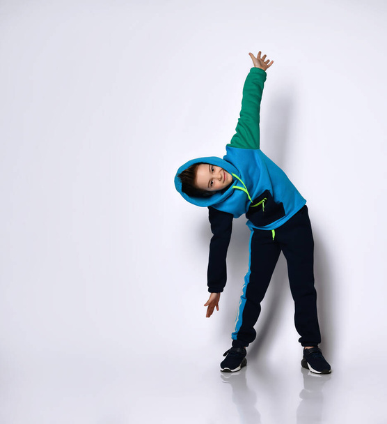 male in hood, colorful tracksuit and black sneakers. He screaming, performing exercises, posing isolated on white - Valokuva, kuva