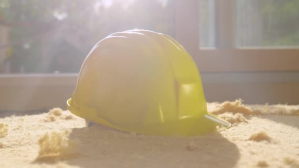 ΚΛΕΙΣΙΜΟ ΠΑΝΩ Ο λαμπερός ήλιος της άνοιξης λάμπει σε ένα κίτρινο σκληρό καπέλο που κάθεται σε φύλλο αφρού - Πλάνα, βίντεο