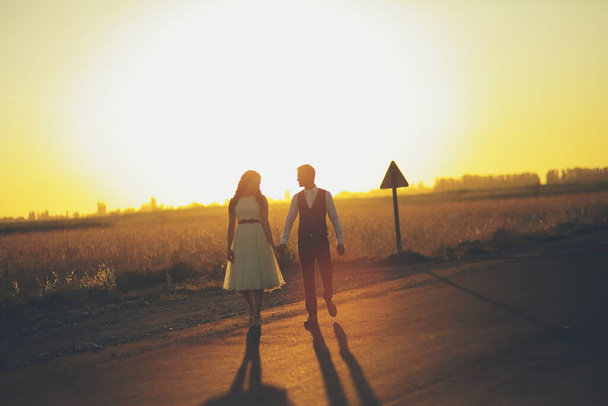 Gli sposi si tengono per mano, si abbracciano e camminano nel parco. Luce del tramonto. Matrimonio. Felice concetto di amore. Foto di alta qualità - Foto, immagini