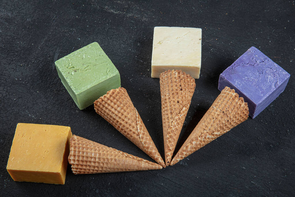 Ice cream cone and natural soaps. Many different handmade soap bars on black wood background. - Foto, immagini