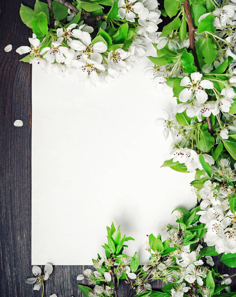 Cartel de papel en blanco y flores de primavera sobre fondo de madera. Disparo vertical. Puesta plana
. - Foto, imagen