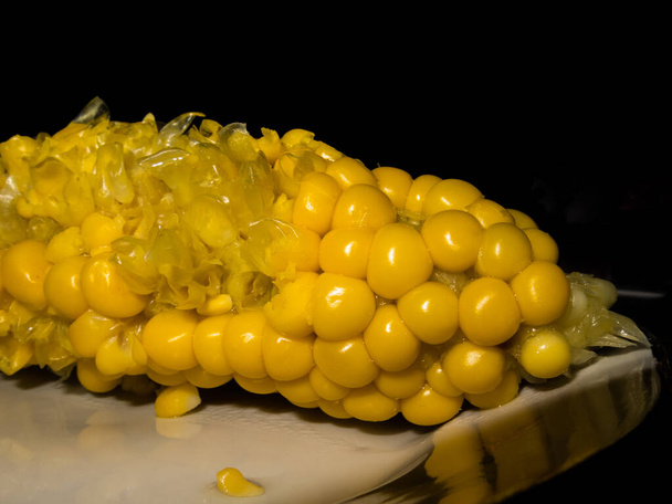 Żółta kukurydza na wpół zjedzona. Czarne tło. Zdjęcie z bliska - Zdjęcie, obraz