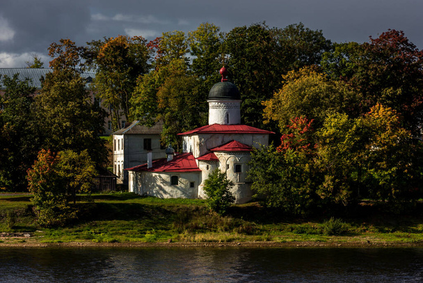 An ancient white Orthodox Christian church on the banks of the Velikaya River in the city of Pskov. Landmark of Russia and the Pskov region - Фото, изображение