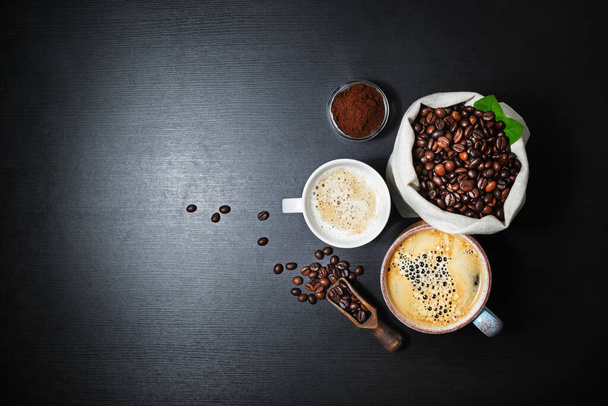 Bodegón con café. Tazas de café y granos de café en bolsa de lona sobre fondo de mesa de cocina negro. Puesta plana
. - Foto, imagen