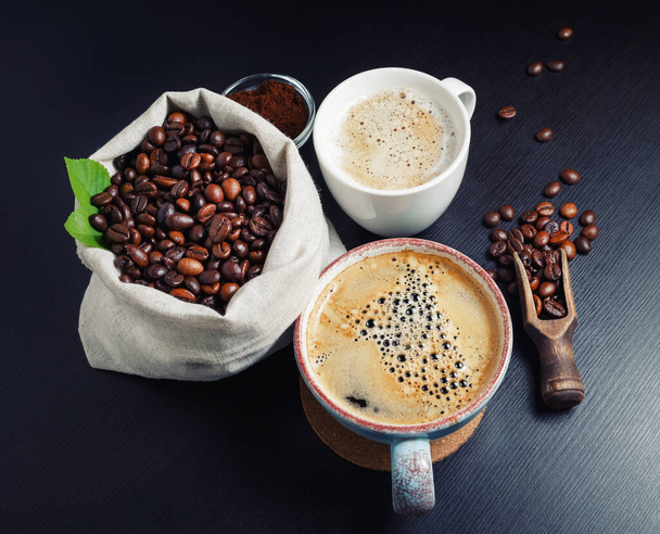 Kaffeetassen mit Kaffeebohnen auf schwarzem Tischhintergrund. - Foto, Bild