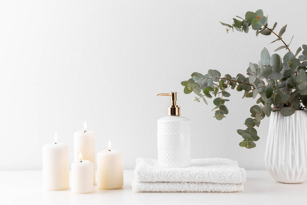 Montón de toallas de baño blancas, jabón, ramo de eucalipto y velas sobre fondo pastel
 - Foto, imagen