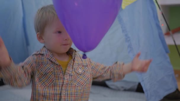 enfance, beau garçon adorable joue avec des ballons colorés - Séquence, vidéo