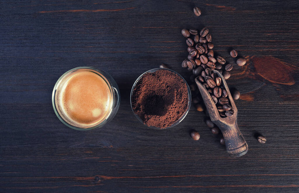 Kaffee-Espresso-Tasse, geröstete Kaffeebohnen und gemahlenes Pulver auf historischem Holzgrund. Ansicht von oben. Flache Lage. - Foto, Bild