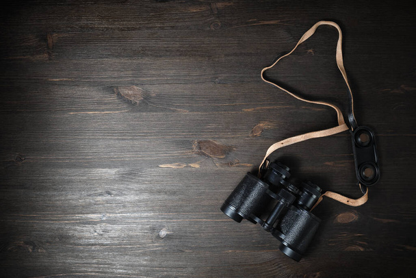 Black military binoculars on wooden background. Lot of copy space for your text. Flat lay. - Photo, image
