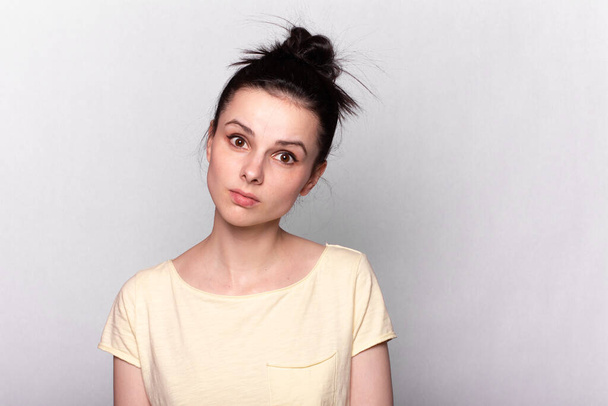 beautiful girl in a yellow T-shirt on a gray background, emotional portrait - Foto, imagen