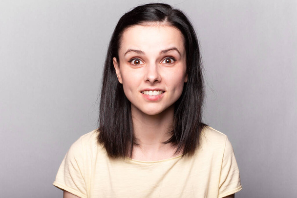 lovely girl in a yellow t-shirt on a gray background - Fotó, kép