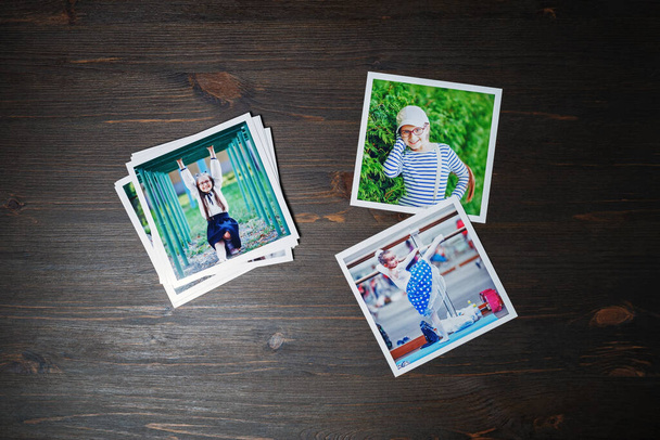 Square photos from a family photo album on wood table background. Flat lay. - Photo, Image