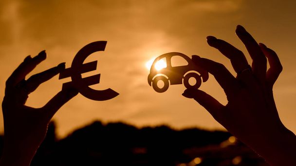 Euro σύμβολο και αυτοκίνητο σε γυναικεία χέρια controued στο ηλιοβασίλεμα - Φωτογραφία, εικόνα