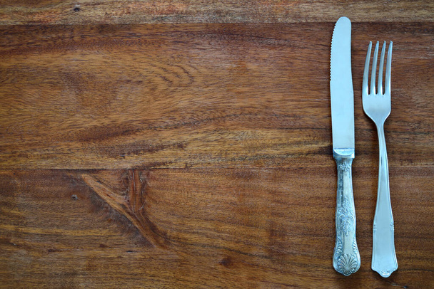暗い木製のテーブルトップの背景には、古いフォークと古いナイフとテキスト用のスペースがたくさんあります。 - 写真・画像