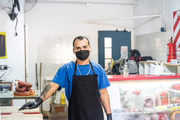 Egy csemegeboltban dolgozó, fekete kötényt viselő munkás. - Fotó, kép