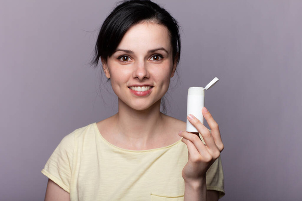 beautiful woman in a yellow t-shirt holding a jar of cosmetic solution - Photo, Image