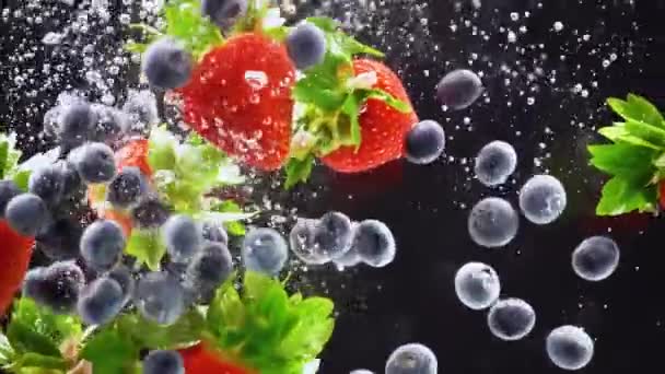 Frische Beeren fallen ins Wasser. Erdbeeren, Blaubeeren planschen im Wasser - Filmmaterial, Video