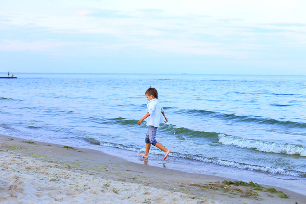海の近くの水の上を少年が走る - 写真・画像