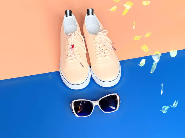 obuv pro ženy růžové tenisky sluneční brýle pro relaxaci čas na modrém a růžovém pozadí - Fotografie, Obrázek