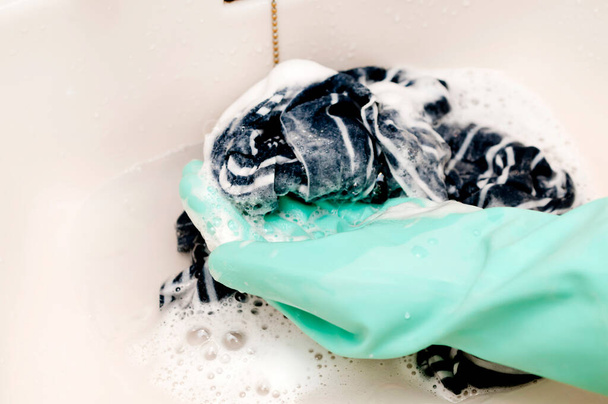 χέρι σε ένα λαστιχένιο γάντι πλένει τα ρούχα - Φωτογραφία, εικόνα