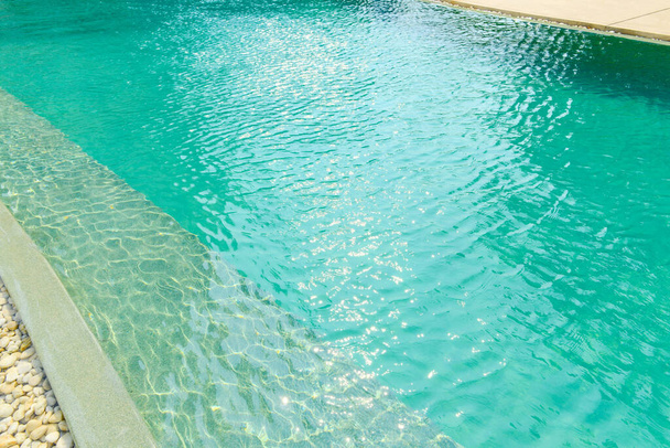 Fechar-se da borda de pedra em frente à piscina azul brilhante. Decoração e design de piscinas com reflexão da luz solar, férias, relaxar, escapadela
 - Foto, Imagem