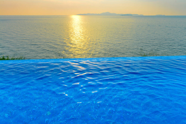 Beautiful view of Infinity Swimming Pool with sunset on the sea at twilight times. - Photo, Image