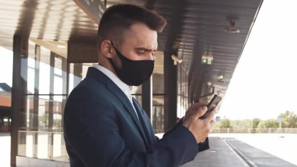 Elegant businessman wearing protective mask in airport. Young mail entrepreneur in formalwear. Pandemic, new rules of control, business trip and traveling concepts. - Záběry, video