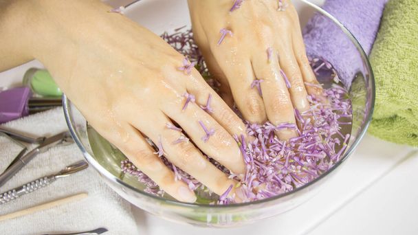 Manicure, paznokcie SPA. Ręce kobiety w wannie z kwiatami. Zmysłowość, pielęgnacja skóry, kobieca, salon, pranie, bogactwo, terapia, kosmetyki, zabiegi, relaks, dayspa, aromaterapia - Zdjęcie, obraz