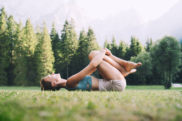 Female practicing yoga on nature. Young woman doing yoga in mountains. Girl with slim, strength and flexibility body doing fitness exercise outdoor. Image of healthy lifestyles and vitality energy. - Foto, imagen