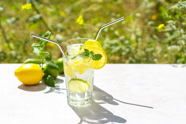 Summer healthy lemonade, cocktails of citrus infused water or mojitos, with lime, lemon, ice, and mint, diet detox beverages in glasses. Blurred background. Copy space for text.  - 写真・画像