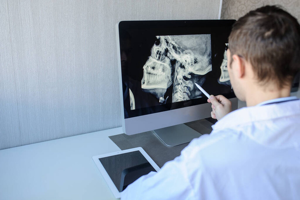vista posterior de un radiólogo masculino que examina las radiografías del cuello (vértebras cervicales) en la computadora
 - Foto, imagen