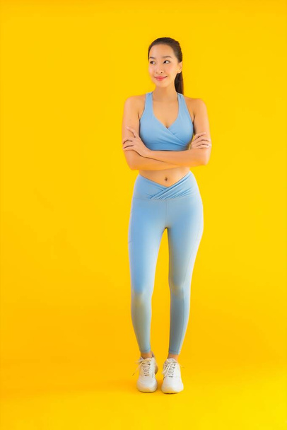 Portret piękny młody azjatycki sport kobieta z odzieży sportowej gotowy do ćwiczeń na żółtym odizolowanym tle - Zdjęcie, obraz
