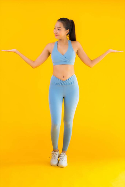Портрет красивая молодая азиатская спортсменка со спортивной одеждой, готовая к упражнениям на желтом изолированном фоне
 - Фото, изображение
