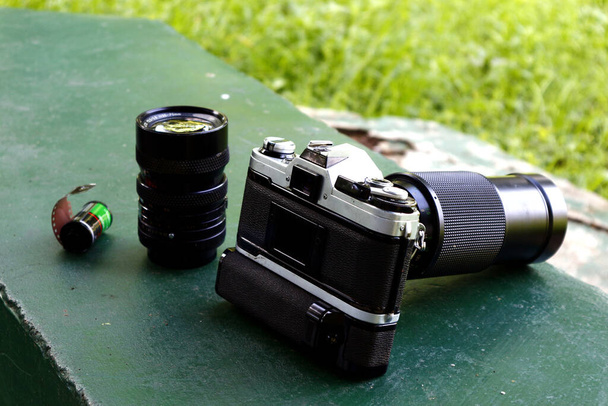 Фото старого і старовинного однооб'єктивного рефлексу або плівкової камери SLR у відкритому парку
. - Фото, зображення