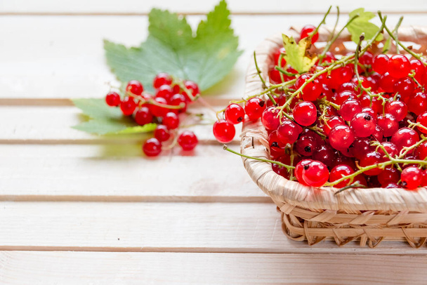 Fresh red currants in bowl on wooden table close up.Ripe large organic red currant in a wicker basket.Summer fresh berries - Photo, image