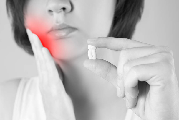 Wisdom tooth extraction, woman suffering from a toothache on gray background, painful area highlighted in red - Foto, Bild