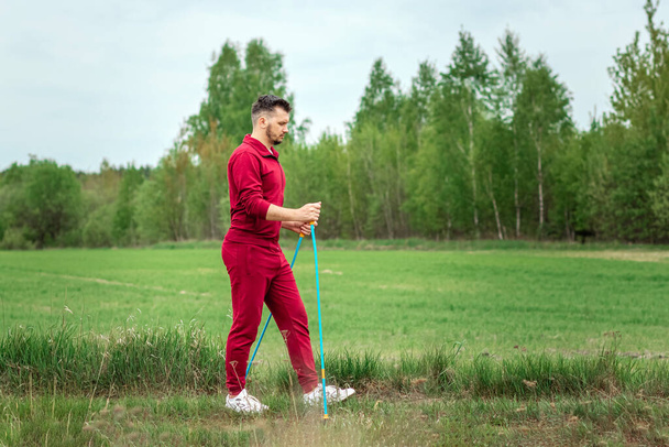 A man in a tracksuit is engaged in Nordic walking. The concept of a healthy lifestyle, cardio training. Copyspace - Fotografie, Obrázek