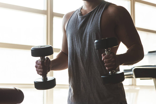 Silhouette picture of a man performing exercises with dumbbells in the gym. Strength training - Foto, Imagem