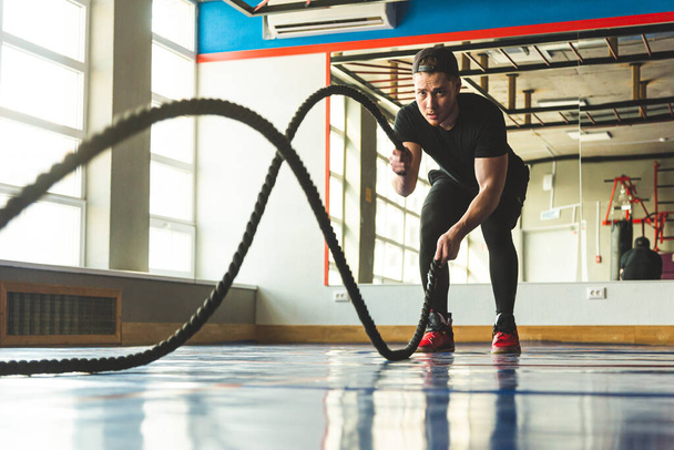 Crossfit in the gym with ropes. The athlete is training. - Foto, Imagem