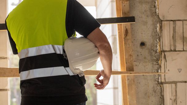 Builder holding helmet on hand, construction site - Photo, Image