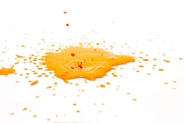 Gotas de agua naranja salpicando sobre un fondo blanco
 - Foto, imagen